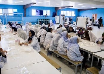 السجينات مجبرات على العمل القسري خلف الجدار المرتفع للسجن.