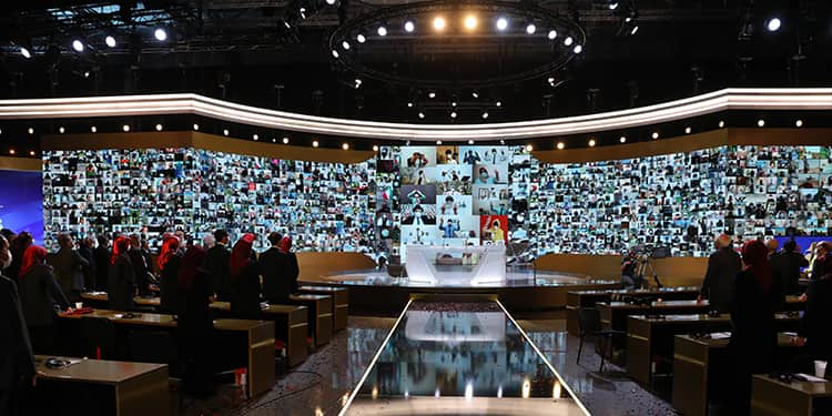 المشاركون في إحدى قاعات أشرف الثالث يصفقون بحرارة لأعضاء وحدات المقاومة الذين عُرضت صورهم على الشاشات الكبيرة.